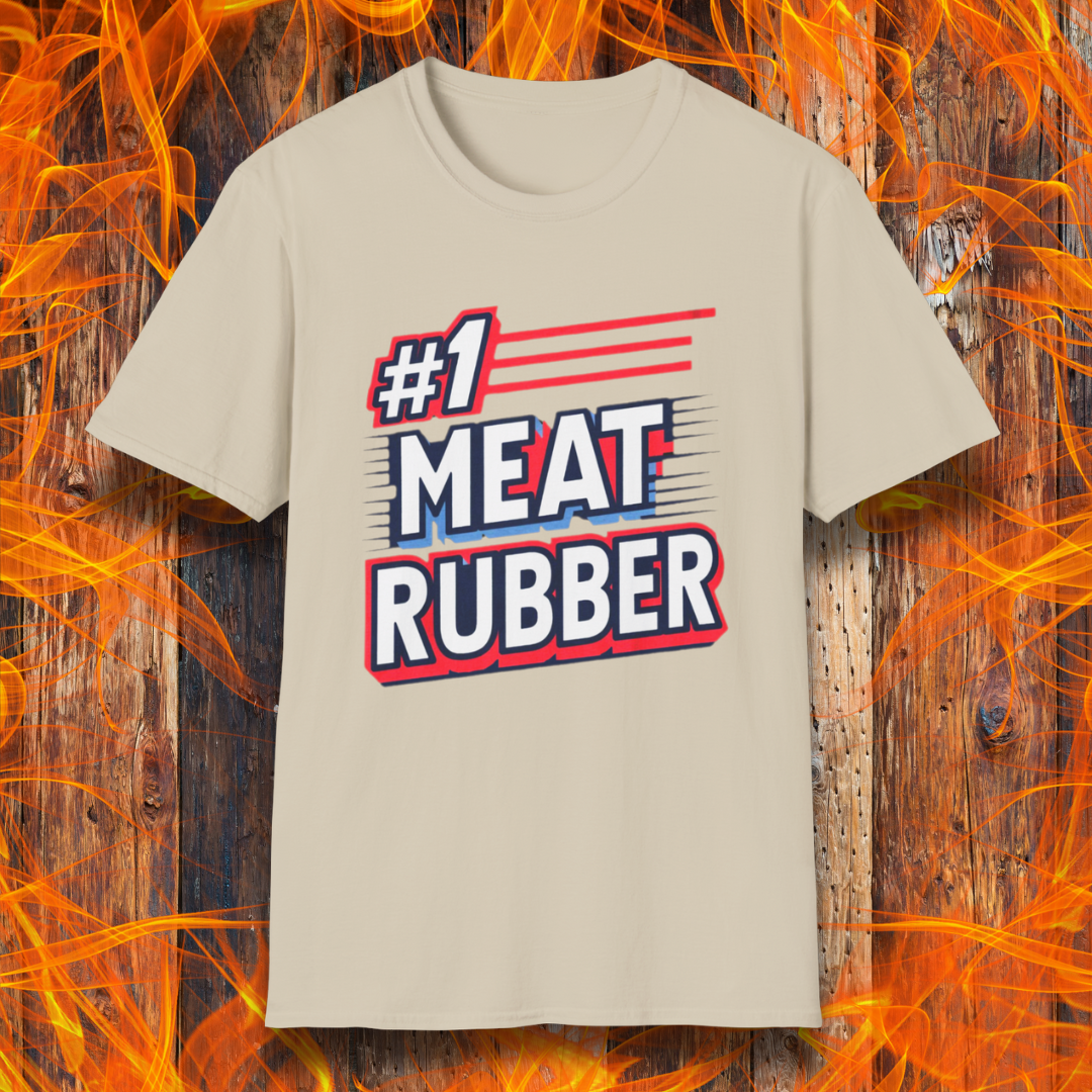 Sand T-shirt featuring a bold and humorous BBQ-themed design that reads '#1 MEAT RUBBER' in white and navy block lettering with red and blue speed-line accents. Perfect for grill masters and barbecue lovers with a sense of humor.