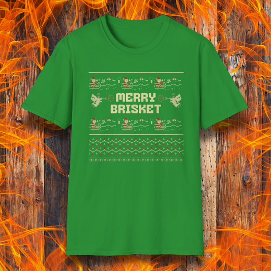 Green t-shirt with 'Merry Brisket' text on a wooden background with flames.