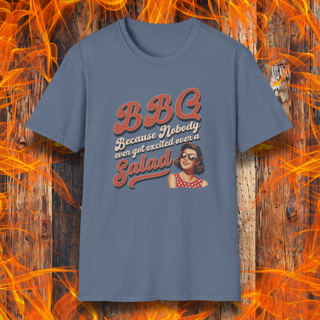 Blue t-shirt with 'BBQ because nobody ever got excited over a salad' text and graphic on a wooden background with flames.