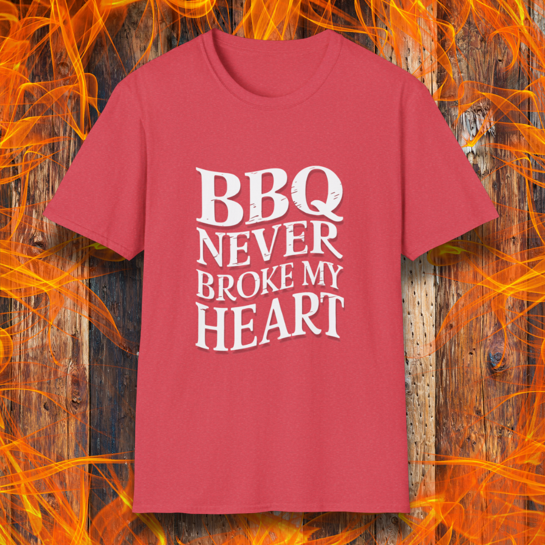Heather red t-shirt featuring bold white text that reads 'BBQ Never Broke My Heart' in a rustic, slightly distressed font, perfect for barbecue lovers who stay loyal to great smoked meats.
