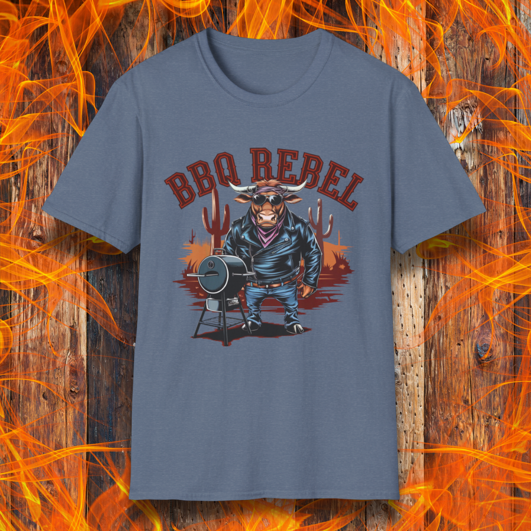 Heather Indigo T-shirt featuring a bold and rebellious BBQ-themed design. The centerpiece is an anthropomorphic bull dressed like a biker, wearing a black leather jacket, blue jeans, and a red bandana, exuding a tough and confident attitude. He stands next to a classic barrel-style smoker. The background includes red flames and grill forks, adding to the edgy, fiery vibe. Above the character, "BBQ REBEL" is displayed in bold, vintage-style red lettering.