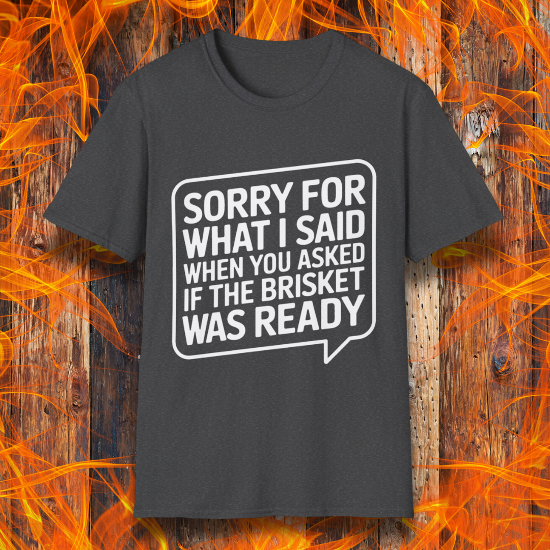 Dark Heather T-shirt with bold white text inside a speech bubble that reads, "Sorry for what I said when you asked if the brisket was ready." A fun and relatable design for BBQ lovers and pitmasters.