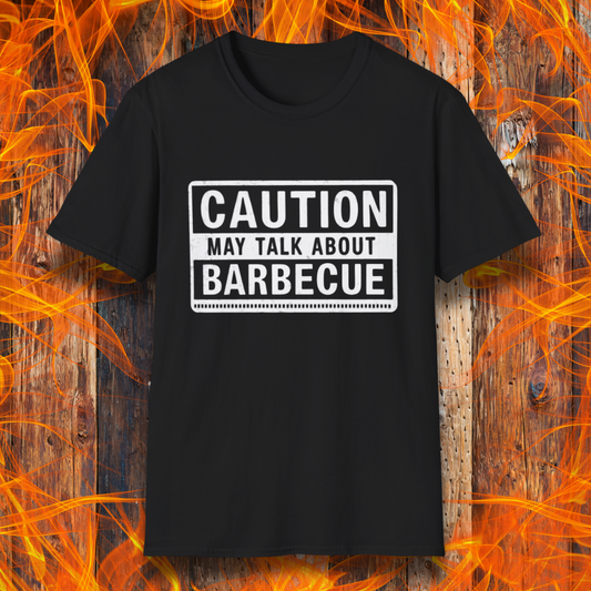 Black T-shirt featuring a bold, high-contrast design resembling a caution sign. The text reads 'CAUTION MAY TALK ABOUT BARBECUE' in white, with a distressed effect, making it perfect for BBQ enthusiasts who love to chat about grilling.