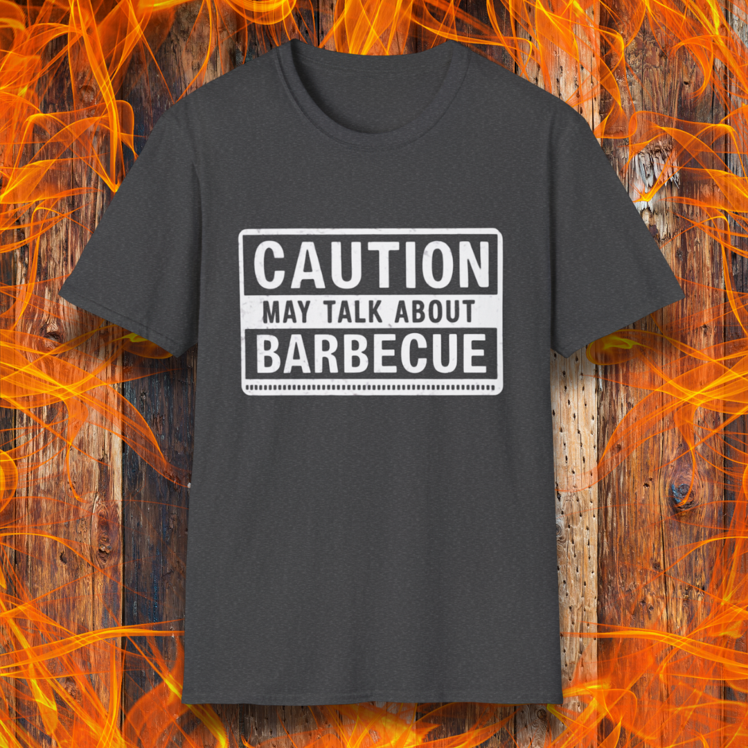 Dark Heather T-shirt featuring a bold, high-contrast design resembling a caution sign. The text reads 'CAUTION MAY TALK ABOUT BARBECUE' in white, with a distressed effect, making it perfect for BBQ enthusiasts who love to chat about grilling.