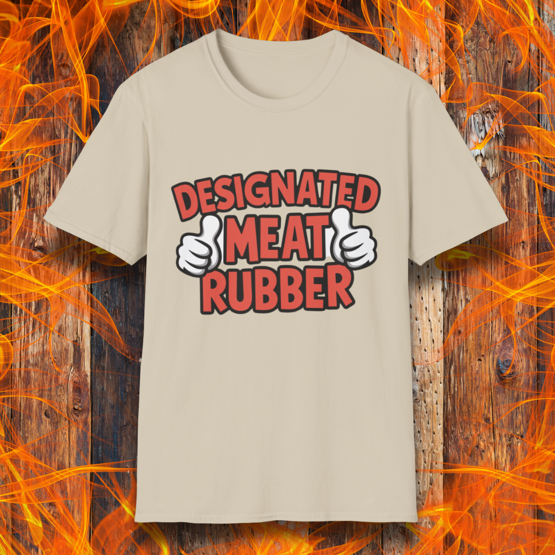Sand T-shirt featuring bold text reading 'Designated Meat Rubber' with two thumbs-up graphics, a humorous BBQ-themed design for grill masters and barbecue lovers.