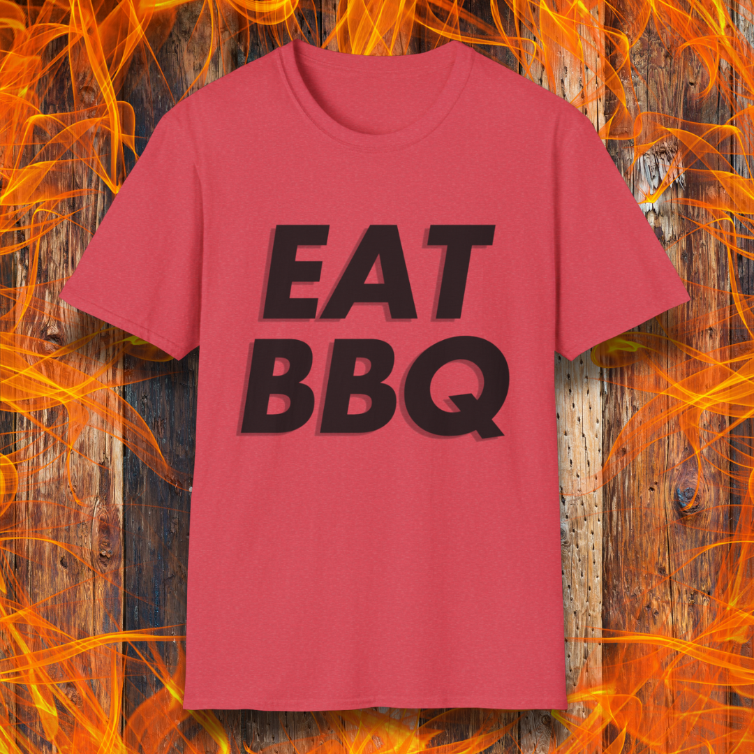 Heather Red T-shirt featuring bold, blocky white text that reads "EAT BBQ" with a 3D effect. The shirt is displayed against a fiery wooden background, emphasizing the BBQ theme.