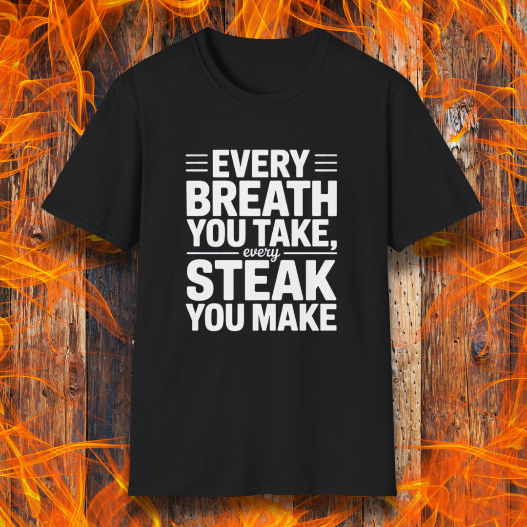 Black T-shirt with bold white text that reads "Every Breath You Take, Every Steak You Make," displayed over a rustic wood and flame background — a humorous grilling shirt perfect for steak fans.