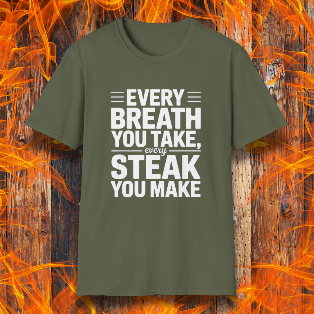 Military Green T-shirt with bold white text that reads "Every Breath You Take, Every Steak You Make," displayed over a rustic wood and flame background — a humorous grilling shirt perfect for steak fans.