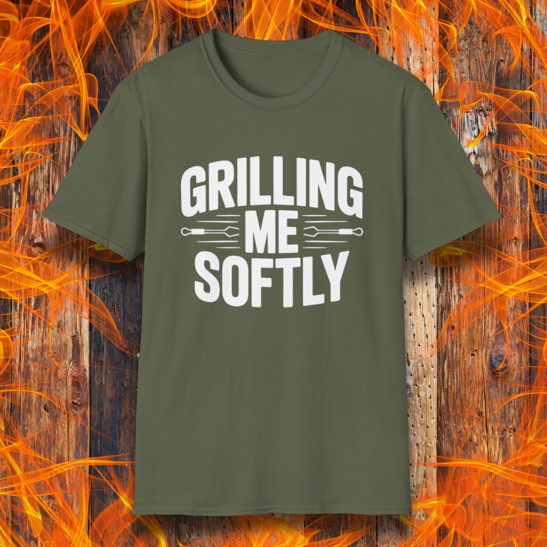 Military Green T-shirt with bold white text that says "Grilling Me Softly," featuring BBQ tool graphics between the words — set against a wood and flame background, perfect for grill lovers with a sense of humor.