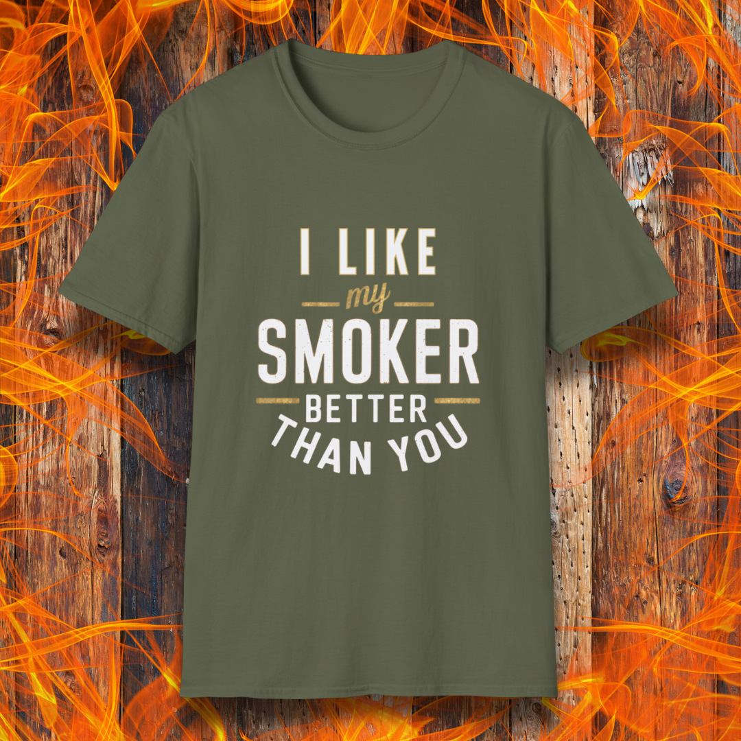 Military Green T-shirt featuring a witty BBQ-themed design. The bold text reads 'I Like My Smoker Better Than You' in a mix of white and gold lettering, with decorative lines adding emphasis. A perfect shirt for grill masters and smoking enthusiasts with a sense of humor.