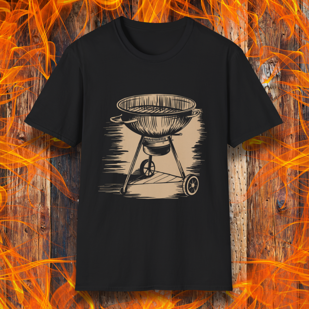 Black T-shirt featuring a vintage-style beige sketch of a classic charcoal kettle grill. The illustration has a hand-drawn, rustic look with shading lines that add depth and texture. The background consists of a wooden surface with bright orange flames, enhancing the fiery BBQ theme.