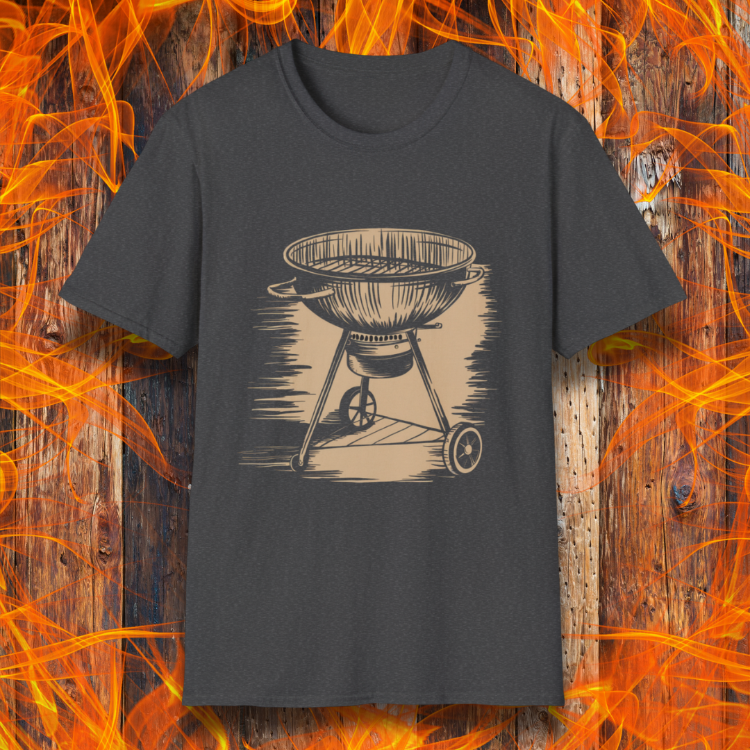 Dark Grey T-shirt featuring a vintage-style beige sketch of a classic charcoal kettle grill. The illustration has a hand-drawn, rustic look with shading lines that add depth and texture. The background consists of a wooden surface with bright orange flames, enhancing the fiery BBQ theme.
