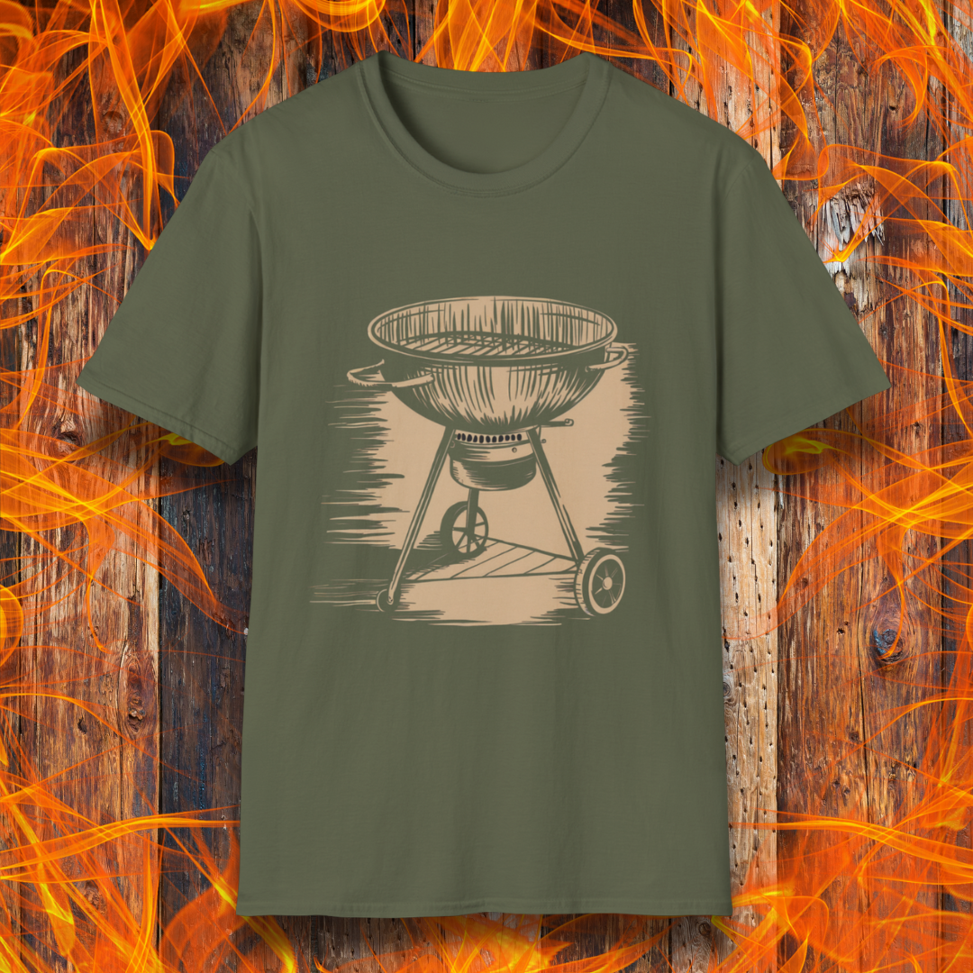 Military Green T-shirt featuring a vintage-style beige sketch of a classic charcoal kettle grill. The illustration has a hand-drawn, rustic look with shading lines that add depth and texture. The background consists of a wooden surface with bright orange flames, enhancing the fiery BBQ theme.