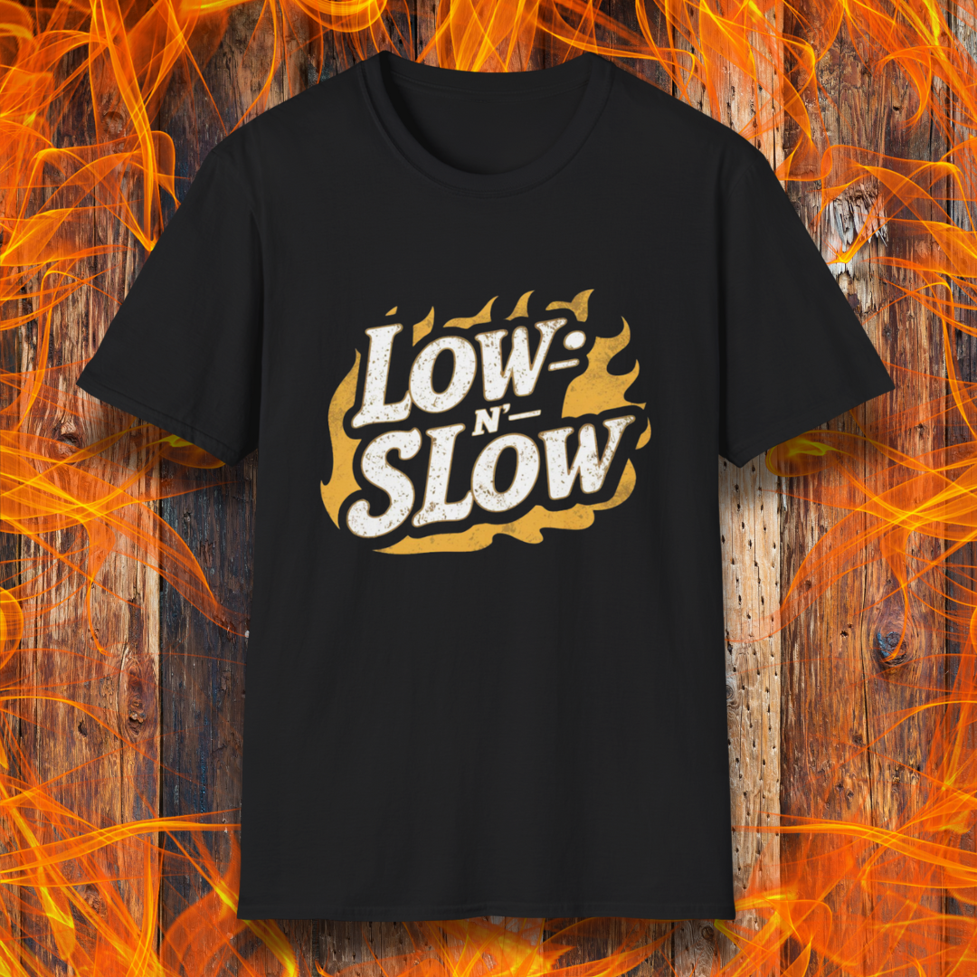 Black T-shirt featuring 'Low-N-Slow' in bold, distressed lettering over a fiery background. Perfect for BBQ pitmasters who know that great barbecue takes time!