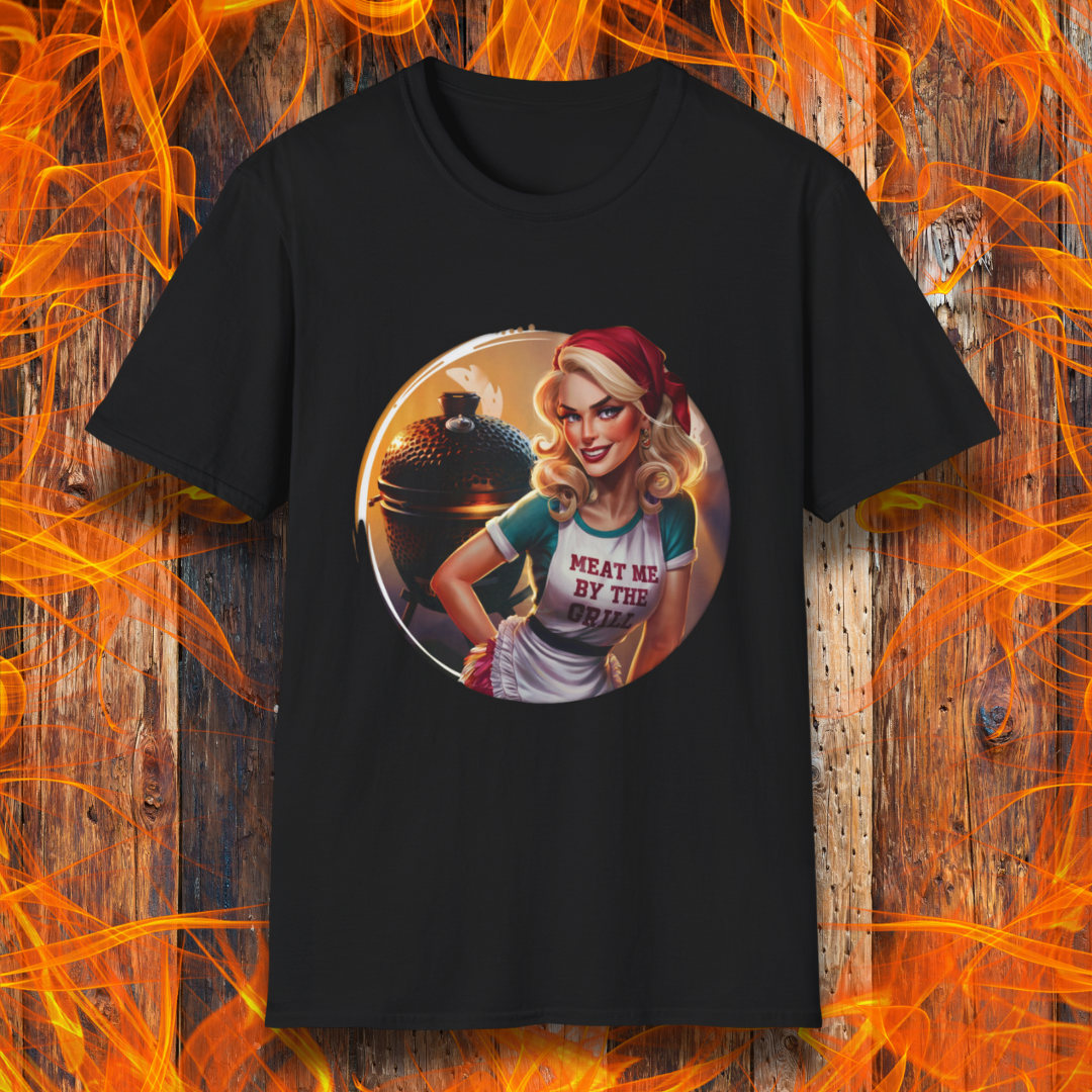 Black t-shirt featuring a vintage-inspired pin-up style woman in front of a charcoal grill, wearing an apron that reads 'Meat Me By The Grill.'"