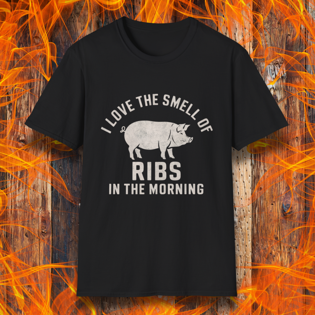 Black T-shirt featuring a vintage-style design with the phrase 'I Love the Smell of Ribs in the Morning' and a rustic, hand-drawn pig illustration. Perfect for BBQ pitmasters and rib lovers!
