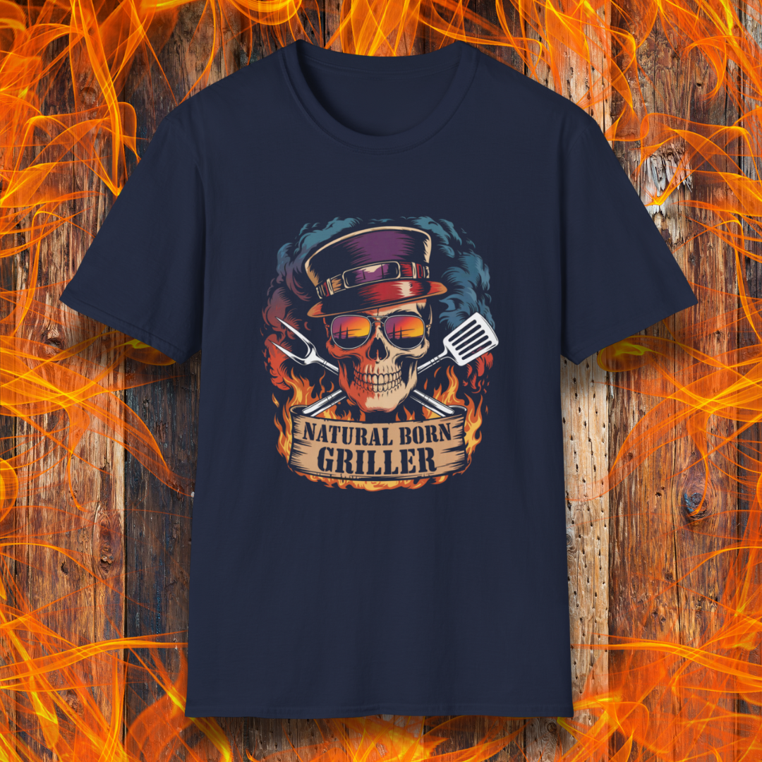 Navy T-shirt featuring a flaming skull in sunglasses and a top hat, flanked by grilling tools with the phrase "Natural Born Griller" — set against a rustic wood and flame background, perfect for bold BBQ enthusiasts.