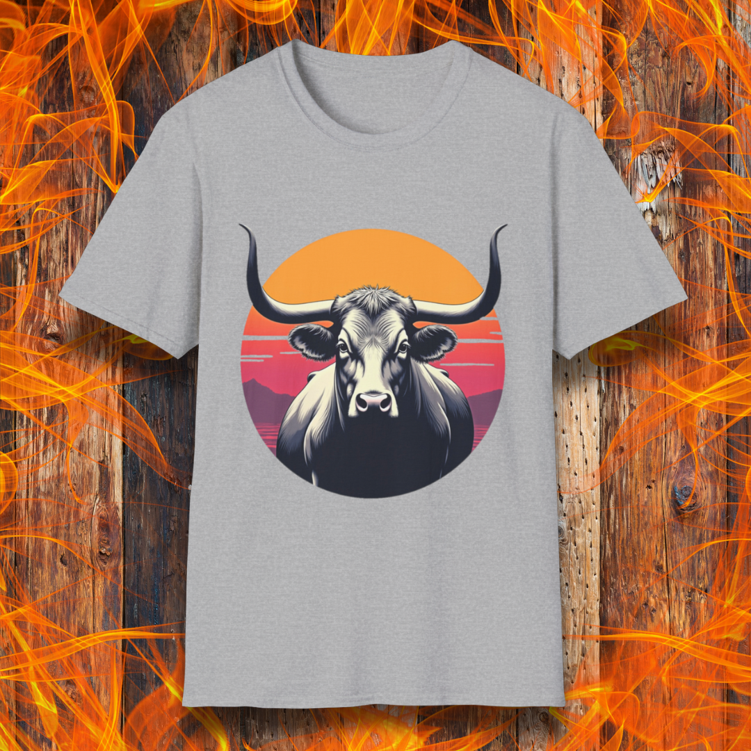 Sport Grey T-shirt featuring a striking design of a longhorn bull staring forward with an intense gaze. The bull is set against a circular backdrop of a sunset with warm orange, red, and pink hues, along with silhouetted mountains in the background. The design conveys strength, confidence, and a bold Western aesthetic, appealing to BBQ and cattle enthusiasts.