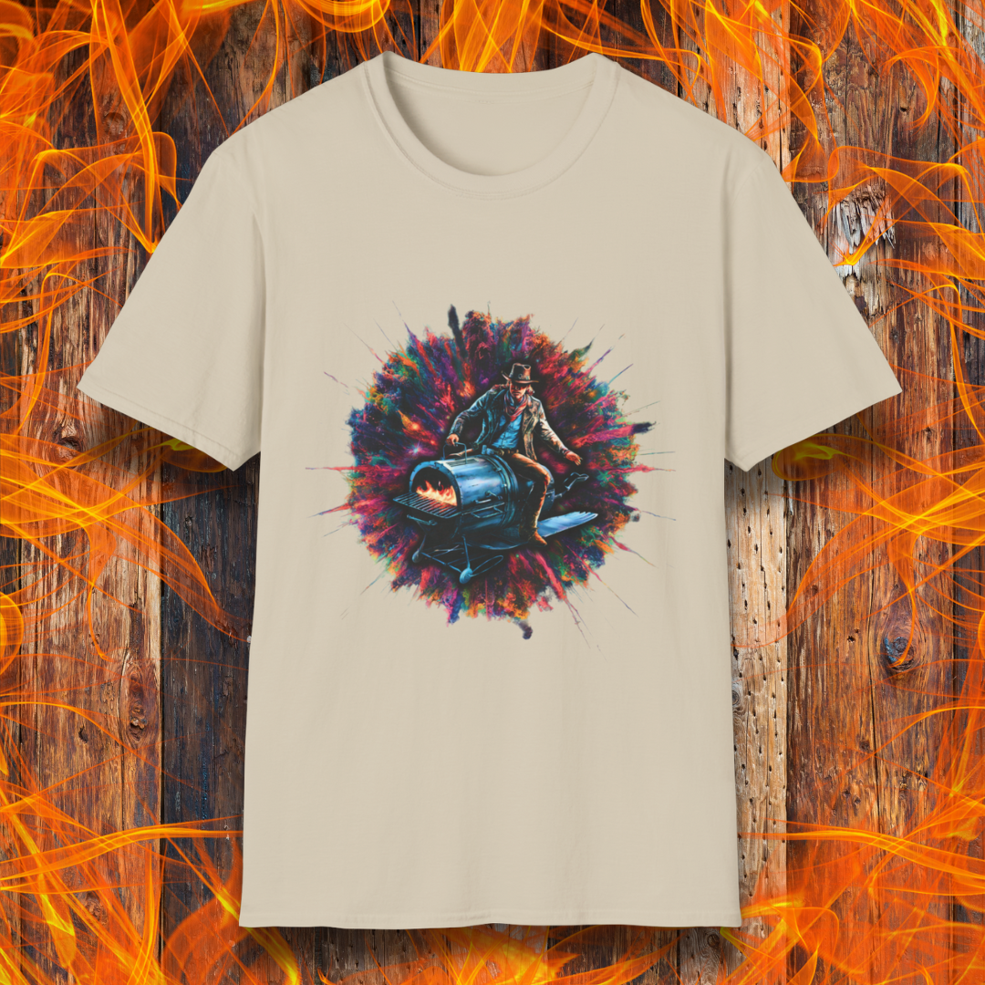Sand T-shirt featuring a striking design of a cowboy riding a futuristic, rocket-powered barbecue smoker. The artwork is set against an explosive, colorful cosmic backdrop, blending elements of Western and sci-fi themes for a bold grilling statement.