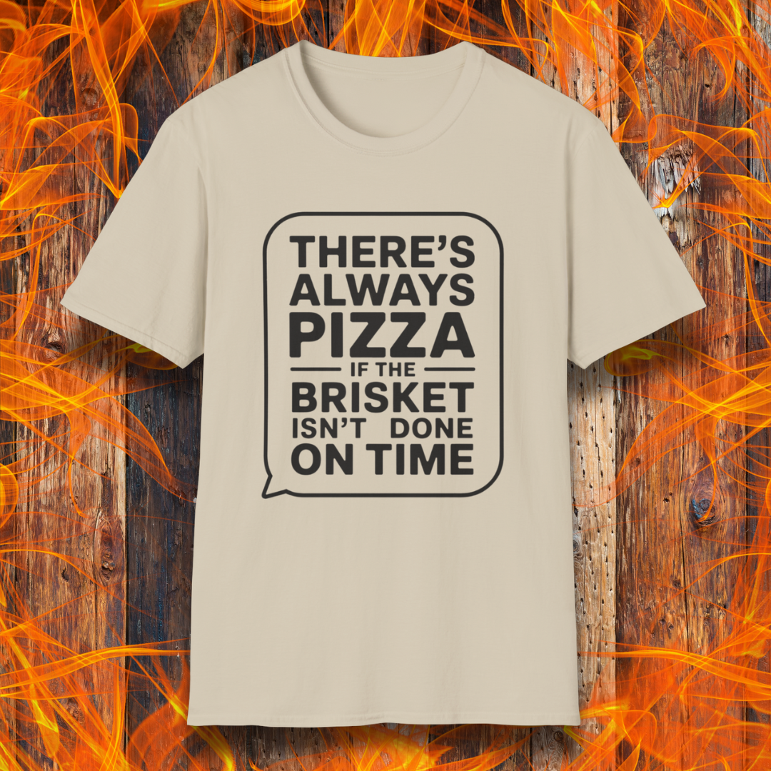 Sand T-shirt featuring bold white text in a speech bubble that reads "There’s Always Pizza If the Brisket Isn’t Done on Time," displayed over a wooden background with flames — a humorous shirt for BBQ fans who know the struggle of low-and-slow cooking.