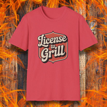 Red t-shirt with 'License to Grill' text on a wooden background with flames.