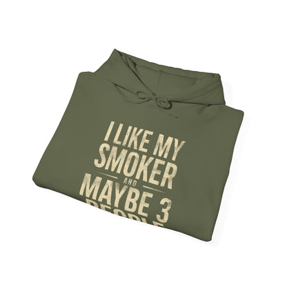 Folded green hoodie with gold text I Like My Smoker and Maybe 3 People” on a white background