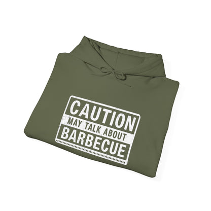 Folded green hoodie with 'Caution: May Talk About Barbecue' text on a white background