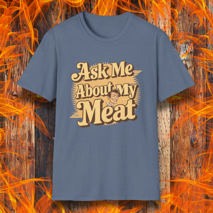 Heather Indigo T-shirt featuring a retro-style design with the phrase 'Ask Me About My Meat' in bold, vintage lettering. The text is accented with a smiling, cartoon-style character, giving it a humorous and playful BBQ-themed vibe.