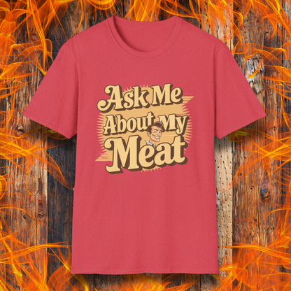 Heather Red T-shirt featuring a retro-style design with the phrase 'Ask Me About My Meat' in bold, vintage lettering. The text is accented with a smiling, cartoon-style character, giving it a humorous and playful BBQ-themed vibe.