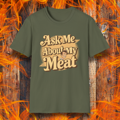 Military Green T-shirt featuring a retro-style design with the phrase 'Ask Me About My Meat' in bold, vintage lettering. The text is accented with a smiling, cartoon-style character, giving it a humorous and playful BBQ-themed vibe.