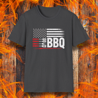 Black t-shirt with American flag and BBQ graphic on a wooden background with flames.
