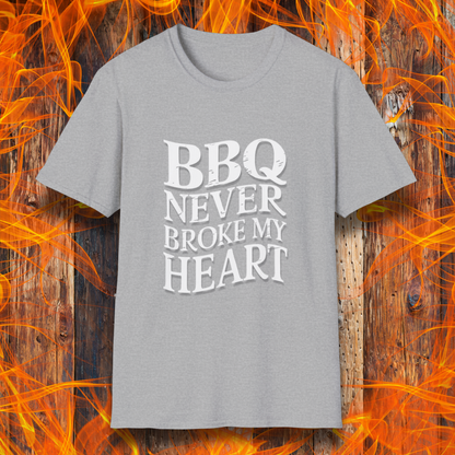 Sport Grey  t-shirt featuring bold white text that reads 'BBQ Never Broke My Heart' in a rustic, slightly distressed font, perfect for barbecue lovers who stay loyal to great smoked meats.