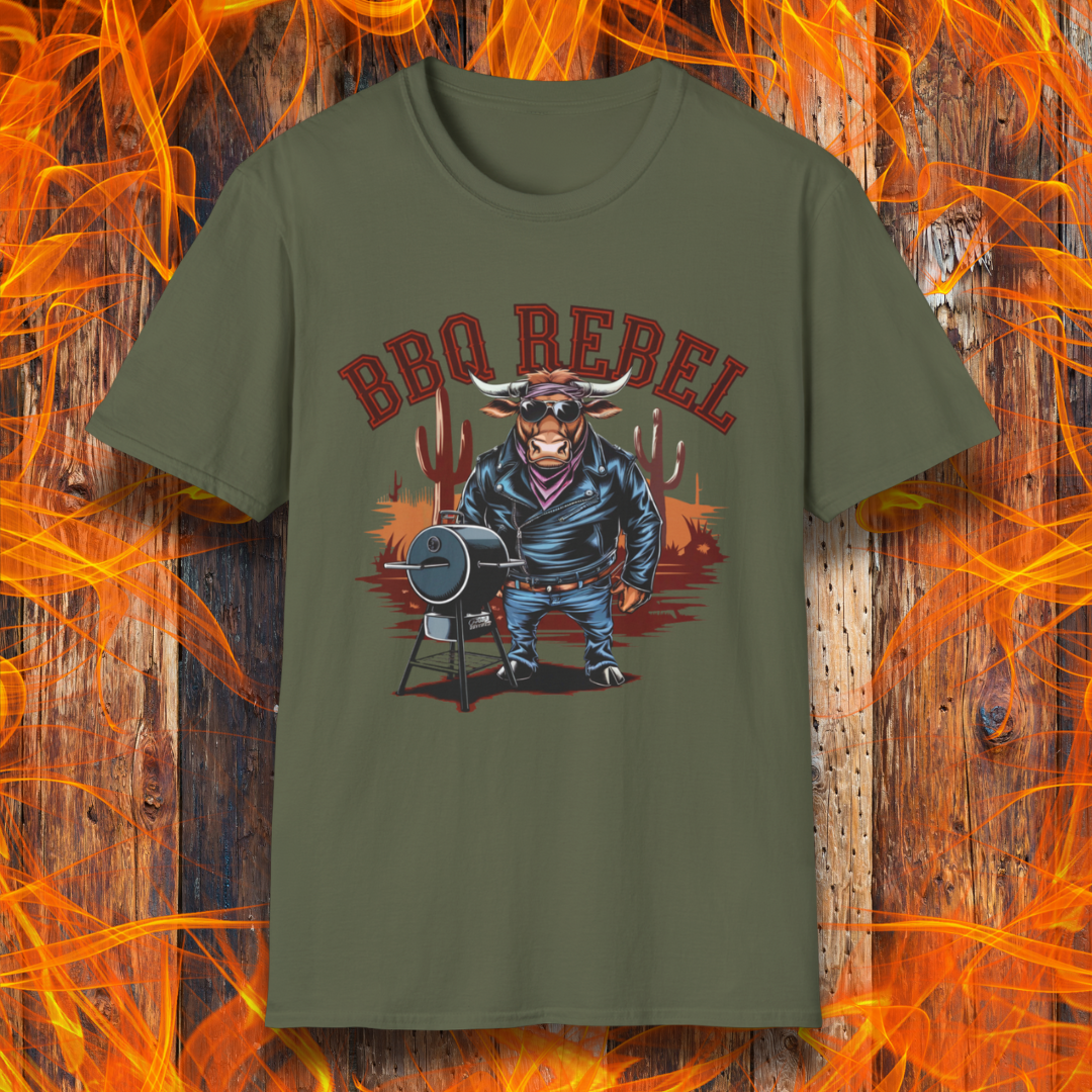 Military Green T-shirt featuring a bold and rebellious BBQ-themed design. The centerpiece is an anthropomorphic bull dressed like a biker, wearing a black leather jacket, blue jeans, and a red bandana, exuding a tough and confident attitude. He stands next to a classic barrel-style smoker. The background includes red flames and grill forks, adding to the edgy, fiery vibe. Above the character, "BBQ REBEL" is displayed in bold, vintage-style red lettering.  