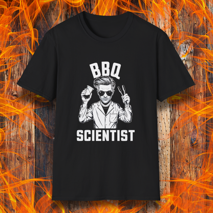 Black t-shirt featuring a bold black-and-white illustration of a cool scientist holding BBQ tongs and a beaker, with the phrase 'BBQ Scientist' displayed above and below."