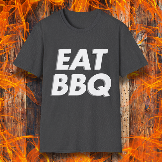 Dark Heather T-shirt featuring bold, blocky white text that reads "EAT BBQ" with a 3D effect. The shirt is displayed against a fiery wooden background, emphasizing the BBQ theme.