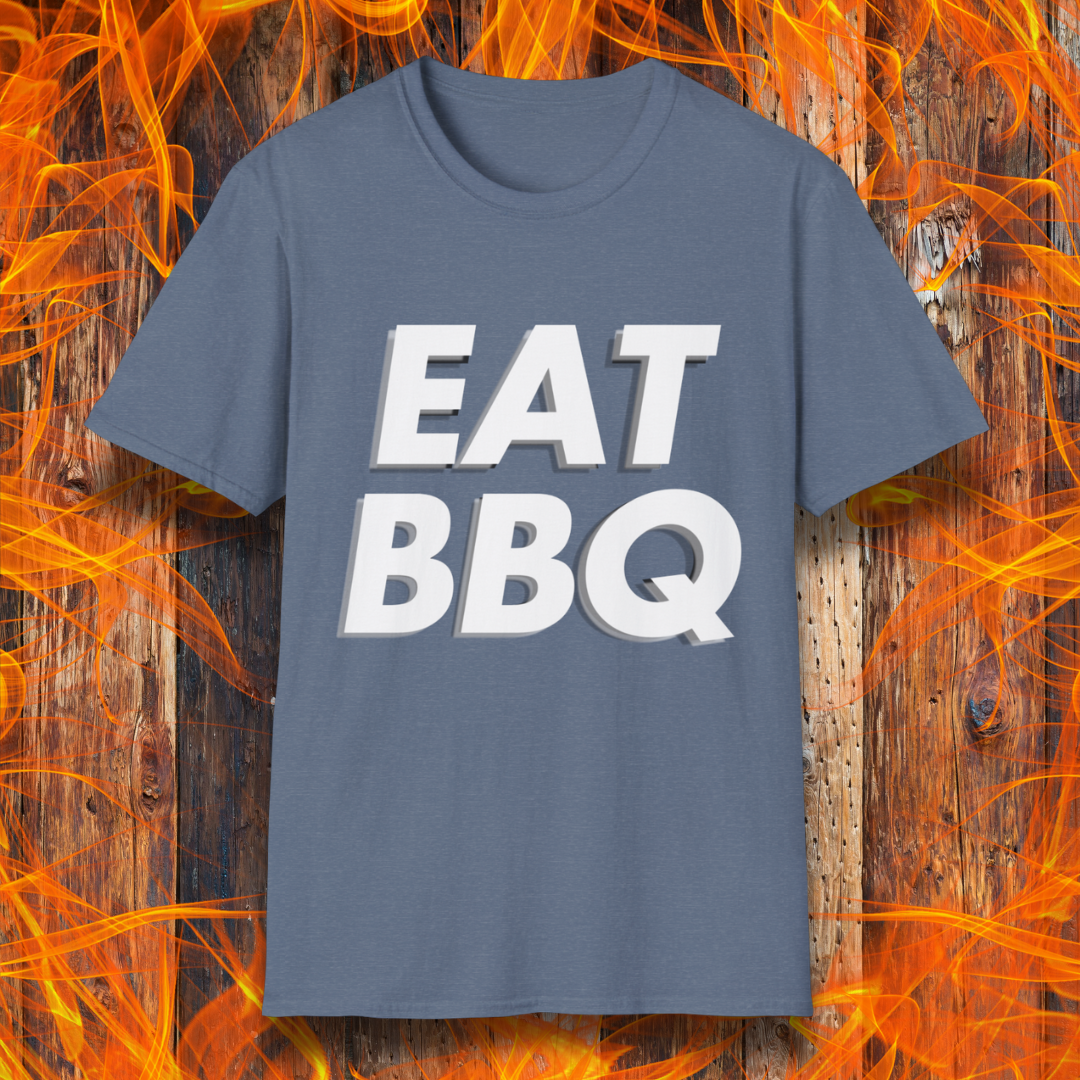 Heather Indigo T-shirt featuring bold, blocky white text that reads "EAT BBQ" with a 3D effect. The shirt is displayed against a fiery wooden background, emphasizing the BBQ theme.