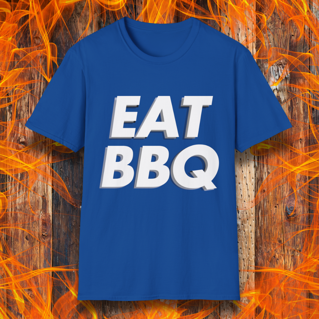 Royal Blue T-shirt featuring bold, blocky white text that reads "EAT BBQ" with a 3D effect. The shirt is displayed against a fiery wooden background, emphasizing the BBQ theme.