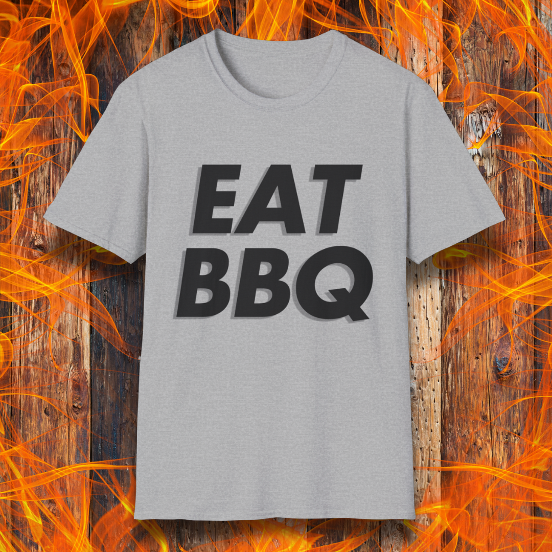 Sport Grey T-shirt featuring bold, blocky white text that reads "EAT BBQ" with a 3D effect. The shirt is displayed against a fiery wooden background, emphasizing the BBQ theme.