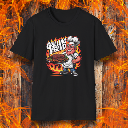 Black t-shirt featuring a cartoon-style chef character holding a platter of perfectly grilled meats, with flames in the background and bold text that reads 'Grilling Legend'—ideal for BBQ masters and pit bosses