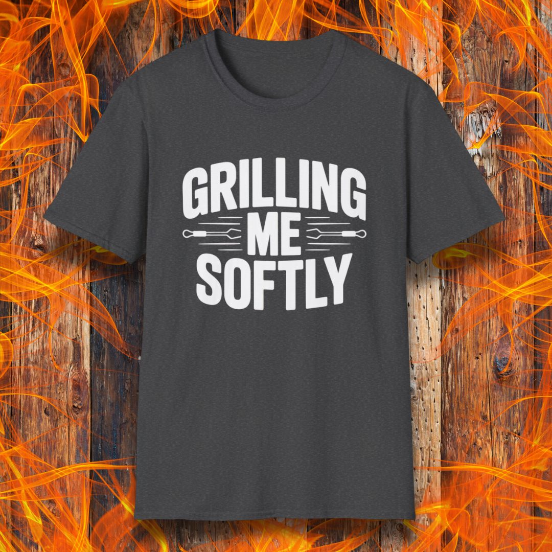 Dark Heather T-shirt with bold white text that says "Grilling Me Softly," featuring BBQ tool graphics between the words — set against a wood and flame background, perfect for grill lovers with a sense of humor.