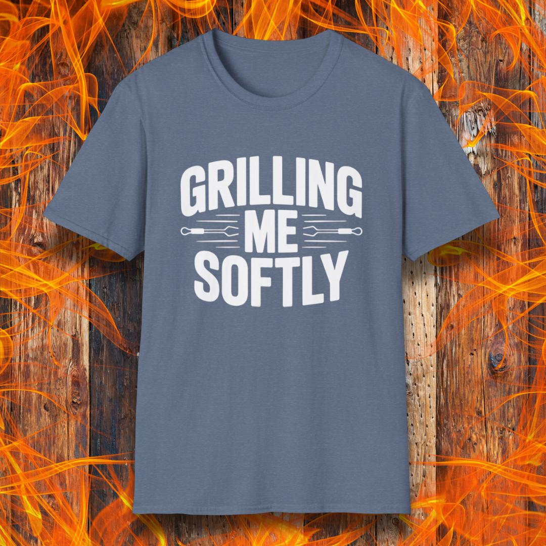 Heather Indigo T-shirt with bold white text that says "Grilling Me Softly," featuring BBQ tool graphics between the words — set against a wood and flame background, perfect for grill lovers with a sense of humor.