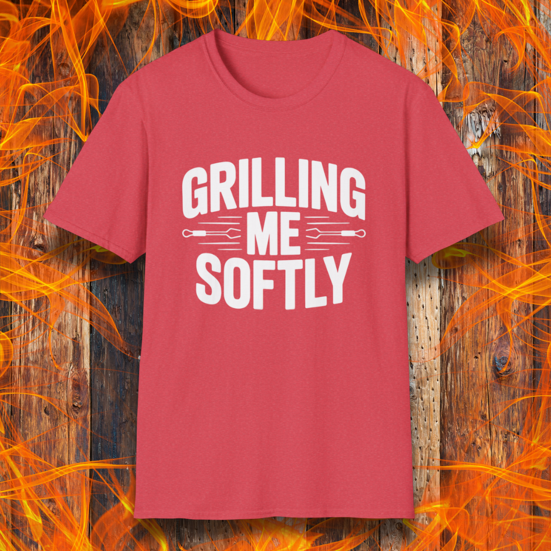 Heather Red T-shirt with bold white text that says "Grilling Me Softly," featuring BBQ tool graphics between the words — set against a wood and flame background, perfect for grill lovers with a sense of humor.