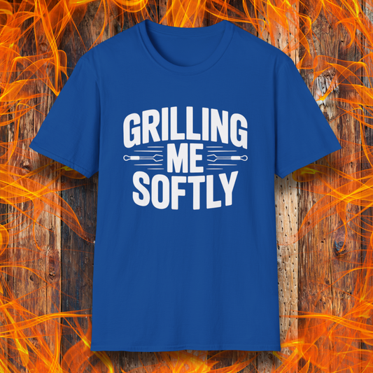 Royal Blue T-shirt with bold white text that says "Grilling Me Softly," featuring BBQ tool graphics between the words — set against a wood and flame background, perfect for grill lovers with a sense of humor.