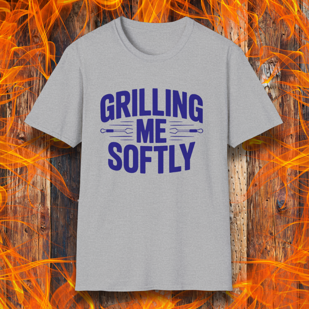 Sport Grey T-shirt with bold white text that says "Grilling Me Softly," featuring BBQ tool graphics between the words — set against a wood and flame background, perfect for grill lovers with a sense of humor.
