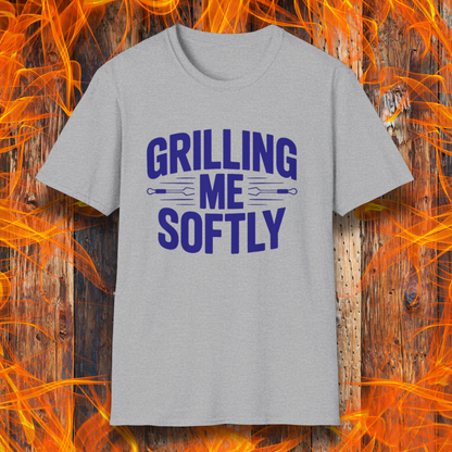 Sport Grey T-shirt with bold white text that says "Grilling Me Softly," featuring BBQ tool graphics between the words — set against a wood and flame background, perfect for grill lovers with a sense of humor.