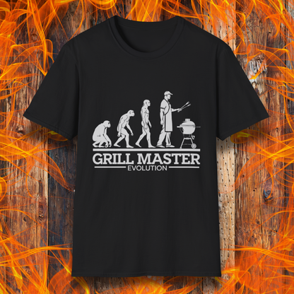 Black T-shirt featuring a humorous "evolution" design that depicts the progression from primate to modern man, culminating in a grill master holding tongs in front of a BBQ grill. Below the illustration, bold white text reads "GRILL MASTER EVOLUTION," emphasizing the ultimate stage of human development—becoming a master of the grill.