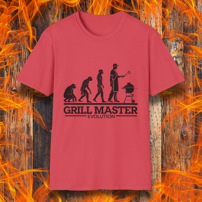 T-shirt featuring a humorous "evolution" design that depicts the progression from primate to modern man, culminating in a grill master holding tongs in front of a BBQ grill. Below the illustration, bold black text reads "GRILL MASTER EVOLUTION," emphasizing the ultimate stage of human development—becoming a master of the grill.