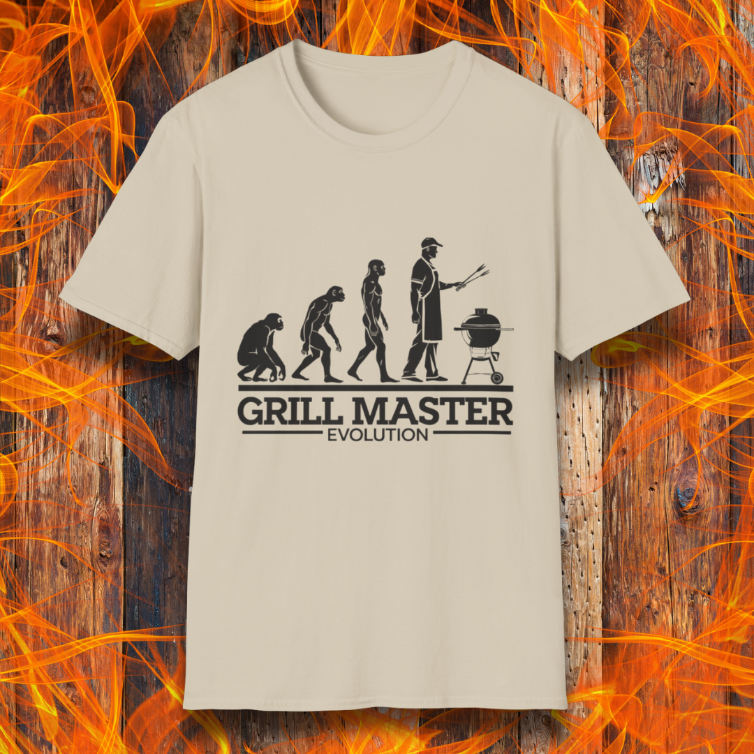 Sand T-shirt featuring a humorous "evolution" design that depicts the progression from primate to modern man, culminating in a grill master holding tongs in front of a BBQ grill. Below the illustration, bold black text reads "GRILL MASTER EVOLUTION," emphasizing the ultimate stage of human development—becoming a master of the grill.