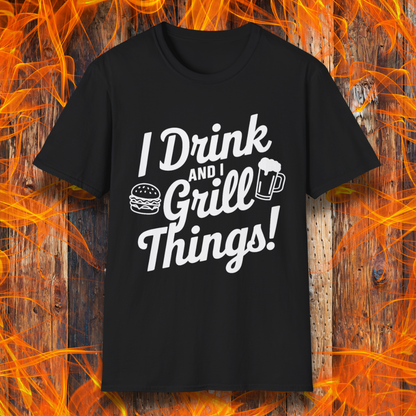 BlackT-shirt featuring a bold, black text design that reads, "I Drink and I Grill Things!" in a playful, script-style font. The design includes small illustrations of a burger and a frothy beer mug, emphasizing a fun and laid-back grilling theme. The background showcases a rustic wooden surface with bright orange flames, enhancing the fiery BBQ aesthetic.