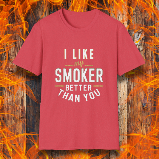 Heather Red  T-shirt featuring a witty BBQ-themed design. The bold text reads 'I Like My Smoker Better Than You' in a mix of white and gold lettering, with decorative lines adding emphasis. A perfect shirt for grill masters and smoking enthusiasts with a sense of humor.